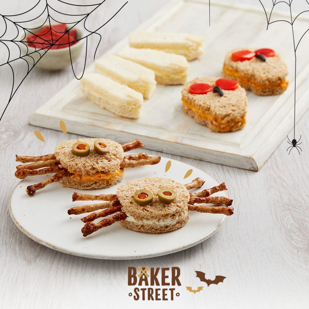 Halloween sandwiches in the shape of spiders, skulls and witches' fingers on a white table